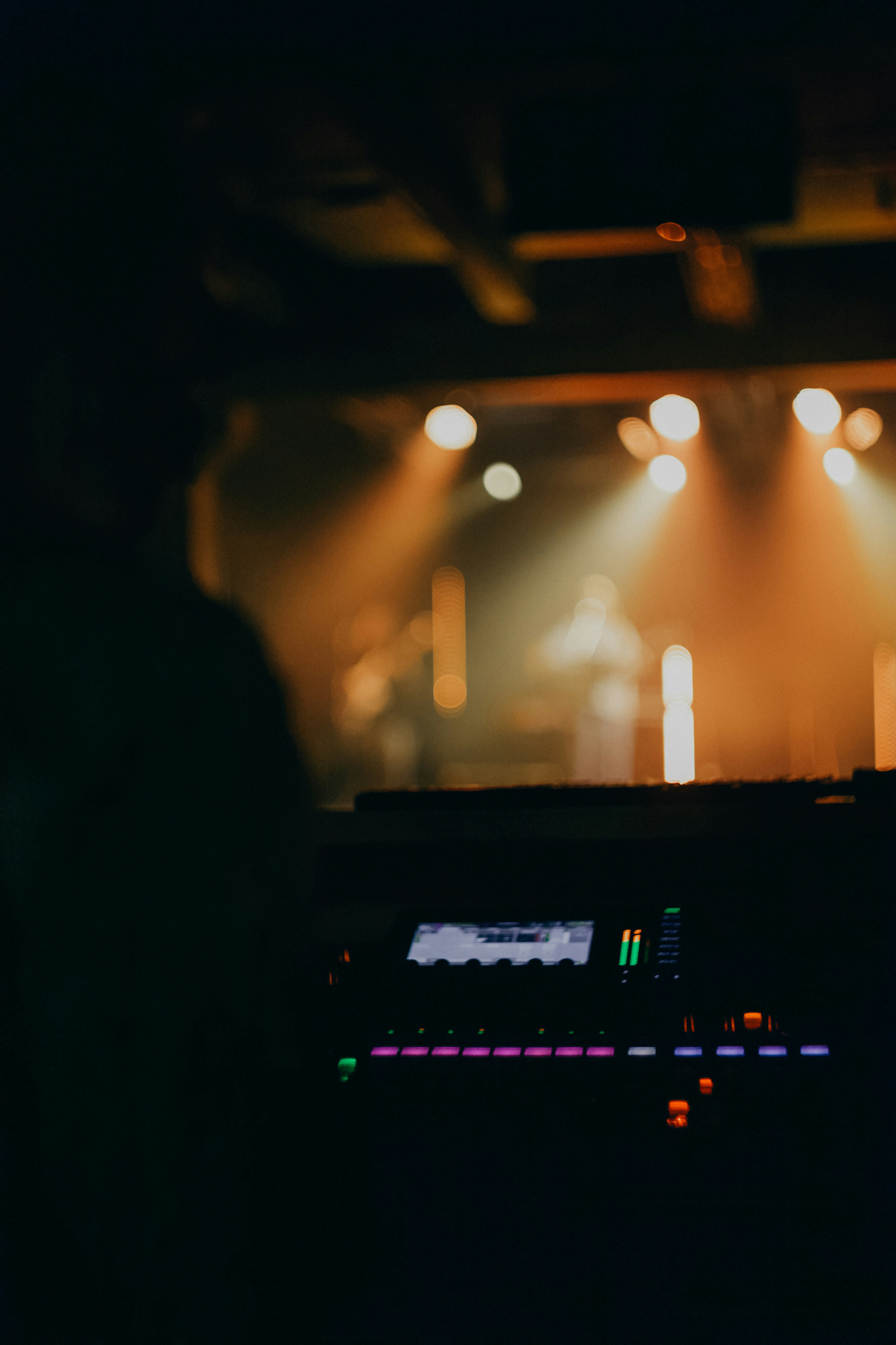 Mixing desk in the foreground with an event stage behind it · illustrative image